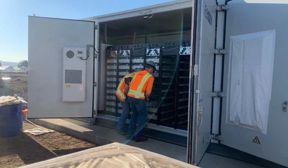Field workers in front of BESS components