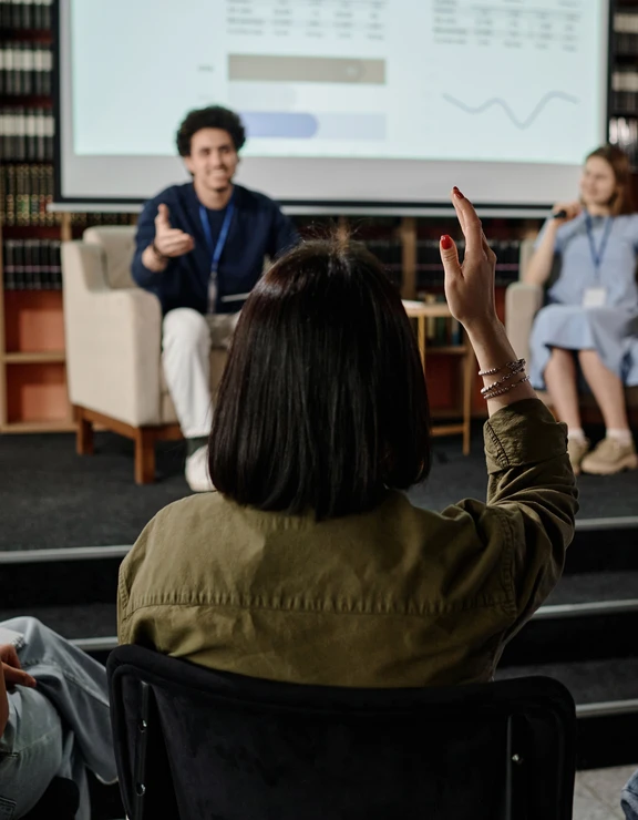 unrecognizable-woman-raising-hand-during-conference